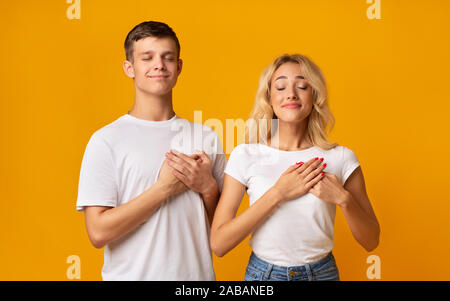 Dankbar junges Paar, beide Handflächen auf der Brust, Wertschätzung zum Ausdruck zu bringen Stockfoto