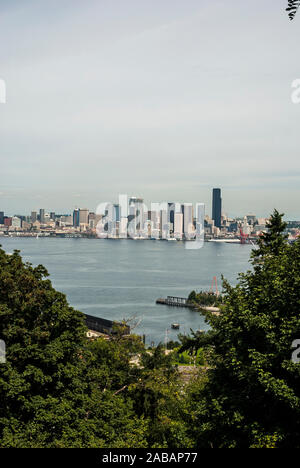 Umrahmt von Laub, eine Aussicht auf die Skyline von Seattle über dem Puget Sound, von West Seattle, Washington. Stockfoto