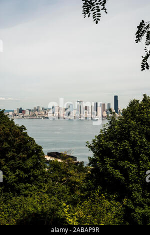 Umrahmt von Laub, eine Aussicht auf die Skyline von Seattle über dem Puget Sound, von West Seattle, Washington. Stockfoto