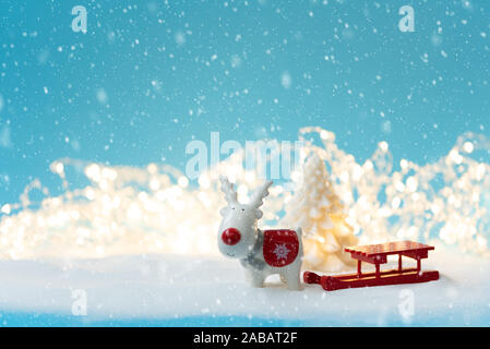 Keramik Weihnachten Rentier Spielzeug, Fir Tree Kerze und Schlitten auf verschneiten und defokussierten Hintergrund leuchten. Weihnachten oder Silvester feiern. Kopieren spa Stockfoto