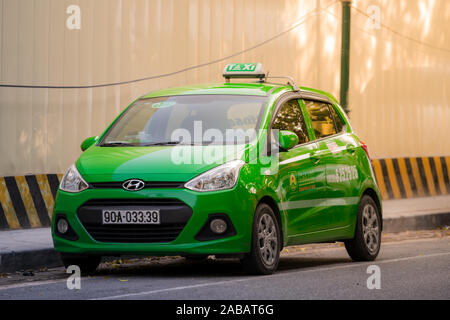 Hanoi, Vietnam - 11. Oktober 2019: ein Mai Linh Hyundai i10 grün Taxi sitzt in den Straßen von Hanoi warten für einen Kunden bei Sonnenuntergang Stockfoto