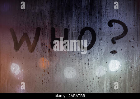 Die quaestion Wer mit dem Finger auf Nacht nasses Glas mit verschwommen Lichter im Hintergrund geschrieben. Stockfoto