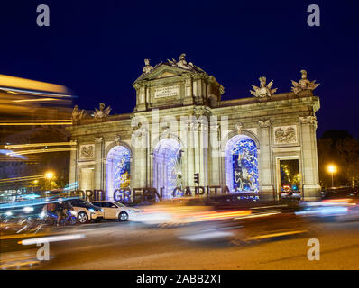 Alcalá-Tor (Puerta de Alcala) bei Einbruch der Dunkelheit durch die Weihnachtsbeleuchtung illuminiert. Independence Square, Ansicht von Alcala Straße. Madrid, Spanien. Stockfoto