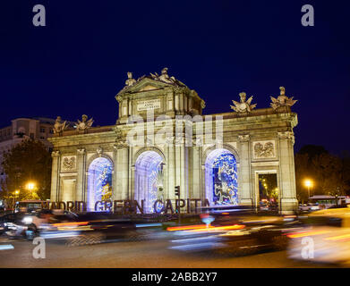 Alcalá-Tor (Puerta de Alcala) bei Einbruch der Dunkelheit durch die Weihnachtsbeleuchtung illuminiert. Independence Square, Ansicht von Alcala Straße. Madrid, Spanien. Stockfoto