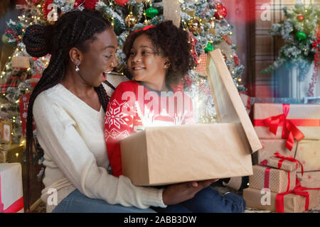 Gerne afrikanische Mutter und Tochter Eröffnung zauberhafte Weihnachten Geschenkverpackung Stockfoto