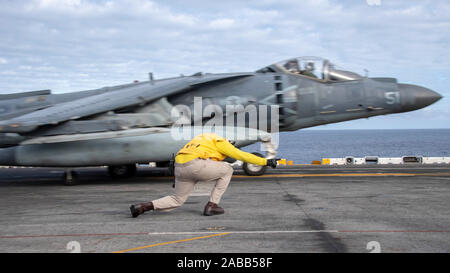 Ein U.S. Navy Senior Chief Aviation Boatswains Mate Cedric Williams Signale an die Pilot eines AV-8B Harrier II fighter Jet für das Flight Deck der USS Boxer im laufenden Betrieb erfolgen November 23, 2019 im Pazifischen Ozean. Stockfoto