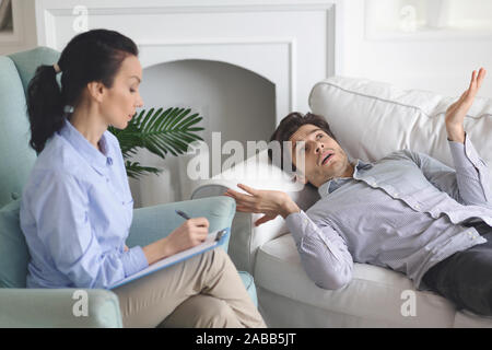 Verwirrt Kerl Verlegung auf Trainer an der Psychologe Cabinet, Gedanken Stockfoto