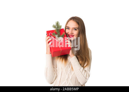 Süße Mädchen in einem weißen Pullover hält ein Weihnachten rot in Ihre Hände und lächelt in die Kamera. Isoliert. Die Blonde ist glücklich über das g zum Neuen Jahr Stockfoto