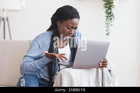 Frustriert afro Mädchen Probleme mit Laptop zu Hause Stockfoto