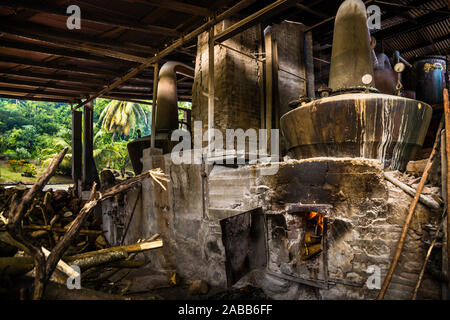 Antoine Rivers Rum Distillery, Saint Patrick, Grenada. Das Holzfeuer brennt unter dem Siedekolben. Die alten Sicherheitsvorschriften sind wahrscheinlich noch ausreichend Stockfoto