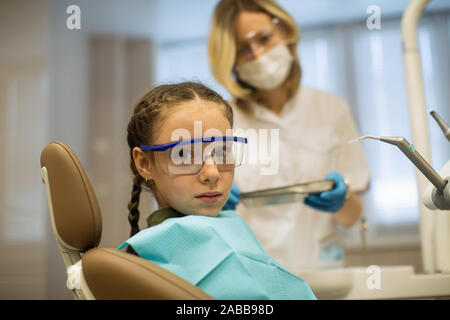 Frau, Zahnarzt, Zähne checkup von kleinen Mädchen schaut besorgt, sitzen in einem behandlungsstuhl Besuch der Medizinischen Klinik. Stockfoto