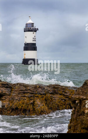 Du Trwyn penmon Leuchtturm (Leuchtturm) auf der östlichen Extremität von Anglesey, Nordwales, mit Wellen über die Felsen brechen Stockfoto