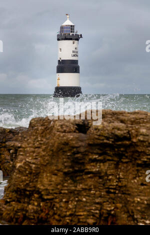 Du Trwyn penmon Leuchtturm (Leuchtturm) auf der östlichen Extremität von Anglesey, Nordwales, mit Wellen über die Felsen brechen Stockfoto