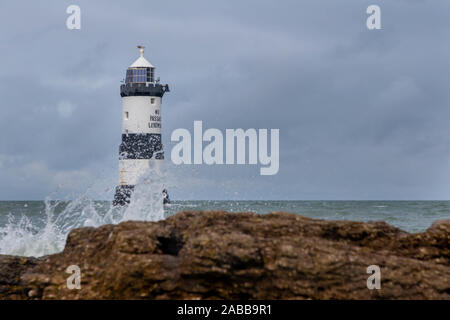 Du Trwyn penmon Leuchtturm (Leuchtturm) auf der östlichen Extremität von Anglesey, Nordwales, mit Wellen über die Felsen brechen Stockfoto