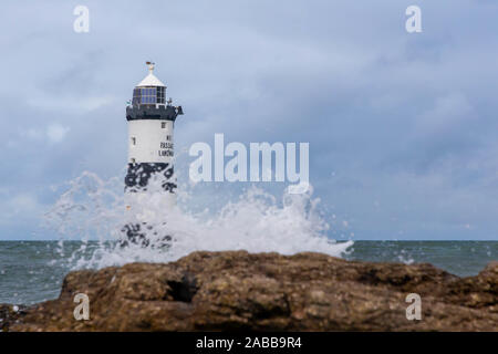 Du Trwyn penmon Leuchtturm (Leuchtturm) auf der östlichen Extremität von Anglesey, Nordwales, mit Wellen über die Felsen brechen Stockfoto