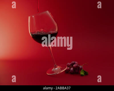Glas Rotwein und ein Bündel von roten Trauben Stockfoto