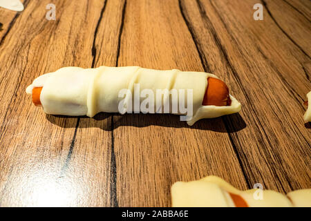 Kleine Würstchen im Teig bestreichen als Snack Stockfoto