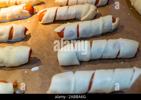 Kleine Würstchen im Teig bestreichen als Snack Stockfoto