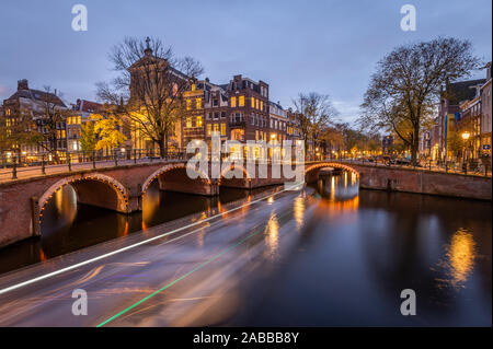 Nacht Blick auf Amsterdam Stadtbild mit Canal, die Brücke und die mittelalterlichen Häuser in der Dämmerung beleuchtet. Amsterdam, Niederlande Stockfoto