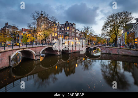 Nacht Blick auf Amsterdam Stadtbild mit Canal, die Brücke und die mittelalterlichen Häuser in der Dämmerung beleuchtet. Amsterdam, Niederlande Stockfoto