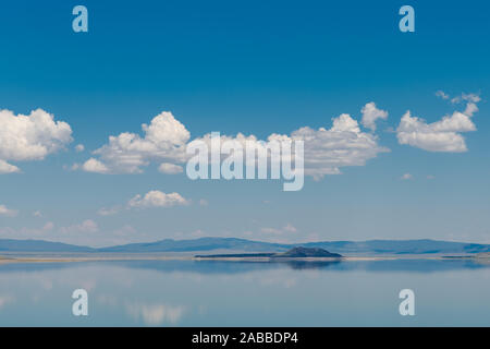 Die ruhige, blaue Wasser des Mono Lake in der Kalifornischen östlichen Sierra ein blauer Himmel mit flauschigen weissen Wolken spiegeln Stockfoto