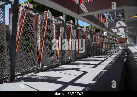 Perspektivische Ansicht des konkreten Balken und Säulen bilden einen leeren Raum durch Metallpaneele und Geländer abstrakte Muster von Licht und sh begrenzt Stockfoto