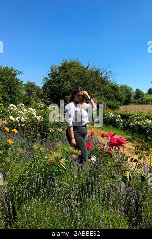 Schöne Frau, die in einem Blumengarten, England, Großbritannien Stockfoto