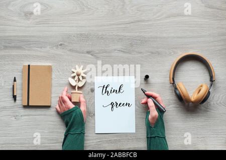 Konzept null Abfall bewussten Konsum Flach, Blick von Oben auf die Hände, die trendigen Holz- Blume und Marker. Text "Think green", Handwerk moleskin noteb Stockfoto