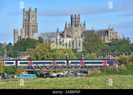 Die Kathedrale von Ely über Zug Bahnhof Ely, Cambridgeshire Boote auf dem Fluss Great Ouse unter Eisenbahnbrücke East Anglia Fens Landschaft England Großbritannien Stockfoto