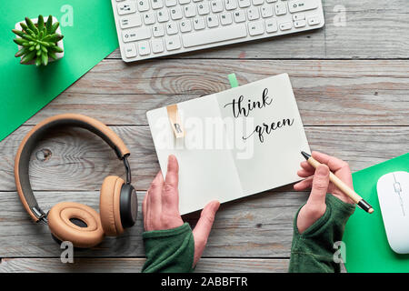 Grün zu Denken, null Abfall creative Flach. Ansicht von oben mit der Hand Notebook mit Motivation Text, Holz- Arbeitsbereich mit Tastatur, Maus, Stockfoto