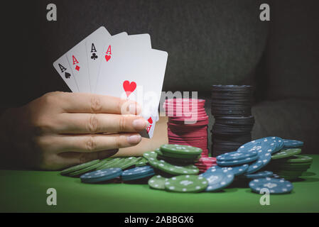 Poker chips auf den Tisch und eine weibliche Hand mit vier Asse schließen oben. Stockfoto