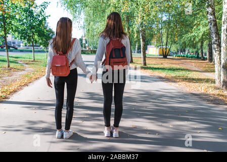 Zwei Mädchen im Teenager-Alter gehen im Sommer im Park, zu Fuß nach Schule und Hochschule, halten Händchen, beste Freunde nach Hause zurück, um nach dem Training mit den Rucksäcken. Kostenlos Stockfoto