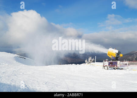 Schneekanone Maschine bläst künstlichen Schnee auf Azuga Skigebiet, Prahova Valley Region, Rumänien, im Winter Nebensaison, aufgrund der fehlenden Natu Stockfoto