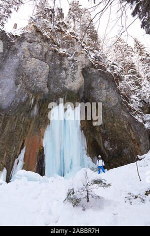 Riesige gefrorenen Wasserfall mit einer Frau, die neben ihm an Sieben Leitern Canyon (sapte Scari) Timisul de Jos, bergen Piatra Mare, Rumänien. Vertikale perspe Stockfoto