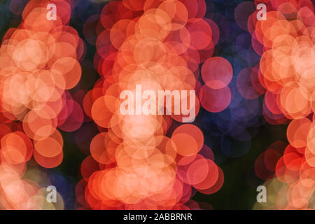 Orange und Rot Weihnachten Licht glänzende abstrakte Runde bokeh auf schwarzem Hintergrund. Bunte Glitzer bokeh von blurry Dekoration Lampen. Stockfoto