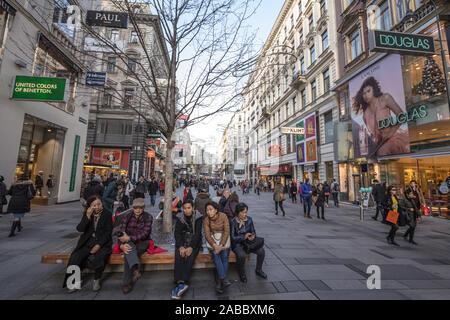 Wien, ÖSTERREICH - NOVEMBER 6, 2019: asiatische Touristen mit einer Unterbrechung und sitzen auf einer Bank in Karntnerstrasse, der wichtigsten Einkaufsstraße der Stadt cent Stockfoto