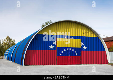 Nahaufnahme der nationalen Flagge Venezuela gemalt auf dem Metall Wand einer großen Lagerhalle das geschlossene Territorium gegen den blauen Himmel. Das Konzept der Stora Stockfoto