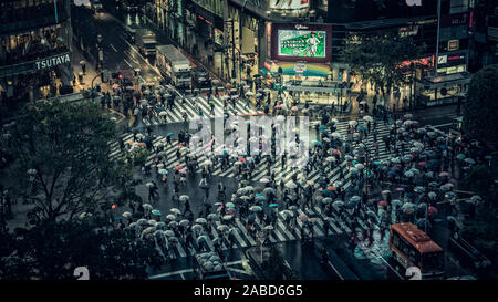 Tokio - 17. APRIL 2017: Shibuya scramble Crossing, einer der belebtesten Fußgängerüberweg in der Welt, Japan. Menschen Überqueren der Straße an regnerischen Eve Stockfoto