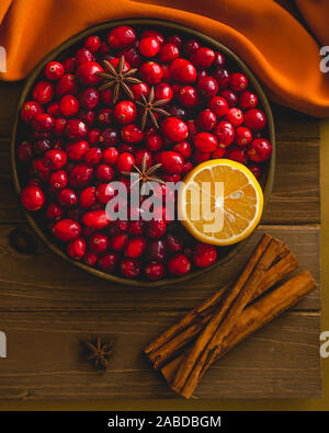 Frische Cranberries, Zimt, Anis, Zitrone schließen bis auf hölzernen Hintergrund Stockfoto