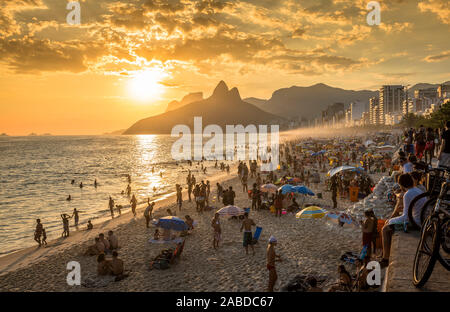RIO DE JANEIRO, BRASILIEN - Februar 2016: Leute beobachten Sonnenuntergang am berühmten Strand von Ipanema in Rio de Janeiro. Rio de Janeiro ist Gastgeber der Olympischen Spiele 2016. Stockfoto