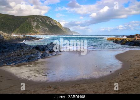 Marine mit Sandstrand, blaues Meer und grüne Berge, Tsitsikamma National Park, Garden Route, Eastern Cape, Südafrika Stockfoto