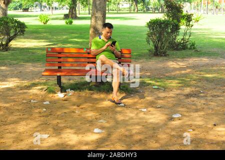 Eine Person sitzt auf einer Bank durch Müll von Touristen in der Nähe der Strand von Yalong Bay Sanya city Links umgeben, der South China Hainan Provinz, am 4. Oktober 2. Stockfoto