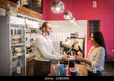 Lächelnd dunkelhaarige Frau kaufen Takeaway Kaffee am Morgen Stockfoto