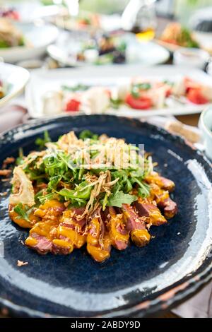 Gebratenes Rindfleisch, Gemüse, Karotte und Austernsauce. In Scheiben geschnitten gegrilltes Rindfleisch Grill Roastbeef Steak und Salat mit Rucola. Verschiedene Snacks und Vorspeisen auf Stockfoto