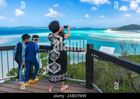 Whitsundays, Australien - Februar 5, 2017: Frau unter Bild von schönen tropischen Lagune mit Ihrem Smartphone bei Hill inlet Lookout Stockfoto