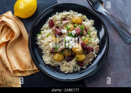 Griechische Lamm mariniert in einem Weißwein salmoriglio Sauce mit neuen Kartoffeln Kalamata Oliven, Feta und Minze garnieren Stockfoto