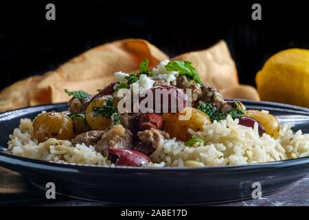 Griechische Lamm mariniert in einem Weißwein salmoriglio Sauce mit neuen Kartoffeln Kalamata Oliven, Feta und Minze garnieren Stockfoto