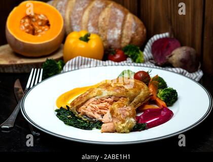 Lachs pie mit gerösteten Kräutern, Gemüse und saurer Sauce serviert. Stockfoto