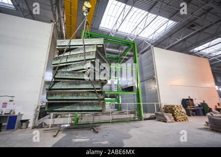 Industriekran trägt Schalung für Betonplatten. Betonwerk. Arbeiter in der Werkstatt des Hauses - Gebäude. Industrial Interior. Stockfoto