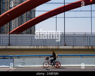 SHANGHAI, China - 12 MAR 2019 - Junge Asiatische chinesische Frau Pendler die Brücke in der Innenstadt von Shanghai auf einem mobike Marke bike Fahrrad. Fahrrad Stockfoto